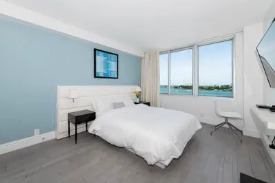 a bedroom with a white bed and a desk and windows at 2 King Rooms Mondrian Resort Skyline Bay Balcony in Miami Beach