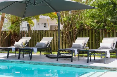 a group of chairs and an umbrella next to a pool at Fox Private Resort- Near Downtown & Beach in Fort Lauderdale