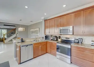 a kitchen with wooden cabinets and stainless steel appliances at Family house with Heated Pool, Walk to Dining in Fort Lauderdale