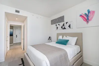 a white bedroom with a bed with a blue pillow at Miami Escape 16th Floor – Near Hollywood Beach in Hollywood