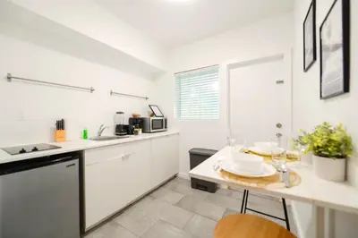 a kitchen with white cabinets and a table with plates on it at Coastal Studio Stay Near the Beach in Miami