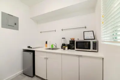 a white kitchen with a microwave and a sink at Coastal Studio Stay Near the Beach in Miami