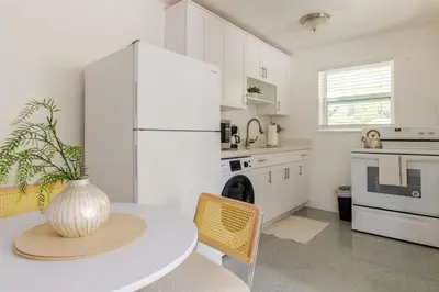 a kitchen with a table and a white refrigerator at Your Modern South Florida Oasis Comfy and Central in Fort Lauderdale