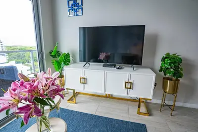 a living room with a large television and plants at Luxury 1BR in Quadro Miami with Pool and Parking in Miami