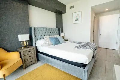 a bedroom with a large bed and a yellow chair at Luxury 1BR in Quadro Miami with Pool and Parking in Miami