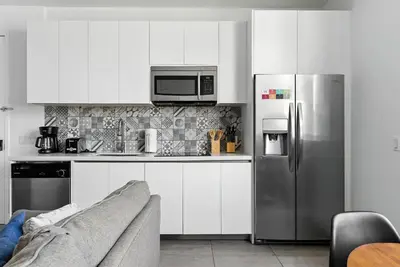 a kitchen with white cabinets and a stainless steel refrigerator at Modern South Beach 2 Bedroom Gem in Miami Beach