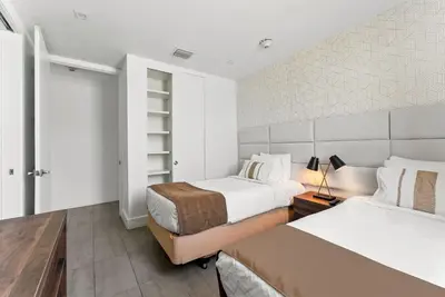 a bedroom with two beds and a night stand with a lamp at South Beach Stylish 2BR Retreat in Miami Beach
