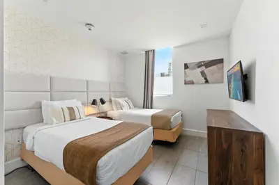a hotel room with two beds and a tv at South Beach 2BR Paradise in Miami Beach