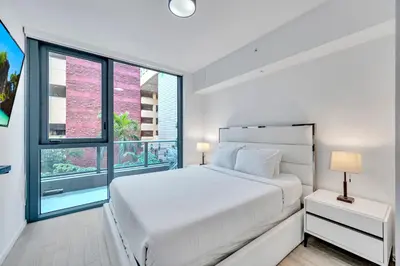 a white bedroom with a bed and a large window at Amazing 3Beds 3Baths Corner Unit Downtown Miami in Miami