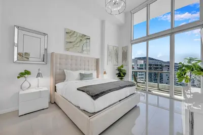 a white bedroom with a bed and a large window at 40th floor High Ceilings unit at icon brickell in Miami
