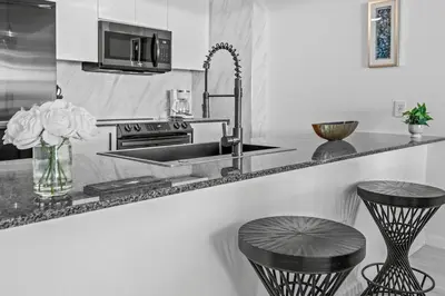 a kitchen with a sink and two stools at High Rise Unit in the heart of Brickell in Miami