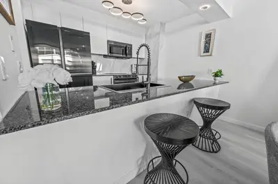 a kitchen with black and white counter tops and stools at High Rise Unit in the heart of Brickell in Miami