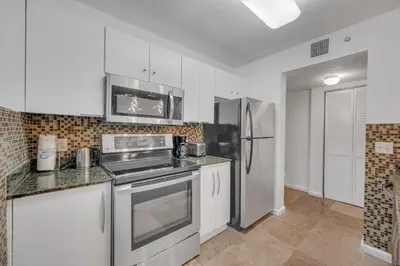 a kitchen with white cabinets and a stainless steel refrigerator at Amazing unit location with amenities & parking in Miami