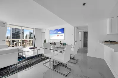a white living room with a glass table and white chairs at Luxurious 34th floor Ocean view Private Unit in Miami