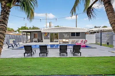 a backyard with chairs and a pool and a house at Luxe 4BR Miami Pool-Near Airport-Games-Backyard in Miami