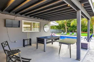 a patio with a ping pong table and a tv at Luxe 4BR Miami Pool-Near Airport-Games-Backyard in Miami