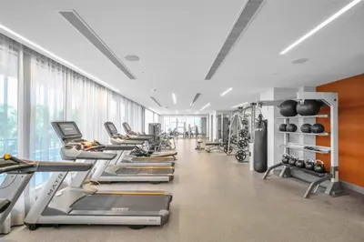 a gym with a row of treadmills and machines at Stylish 3BD-3BR at the Heart of Downtown Doral with Top Amenities & Golf in Miami