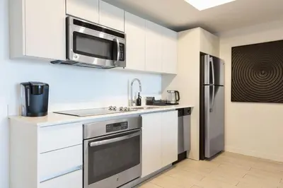 a kitchen with white cabinets and a stainless steel refrigerator at 2 Bed & 2 Bath at Beachwalk - Amazing View on 29th in Hallandale Beach