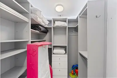 a walk in closet with white shelves and a red door at WATERFRONT Luxury 3 Bed 3 Bath Suite in Hallandale Beach