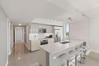 a kitchen with white cabinets and a counter with stools at WATERFRONT Luxury 3 Bed 3 Bath Suite in Hallandale Beach
