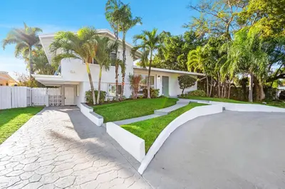 a house with palm trees and a driveway at Fort Lauderdale Water Front Oasis in Fort Lauderdale