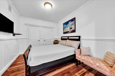 a white bedroom with a bed and a chair at South City Suites in Hallandale Beach