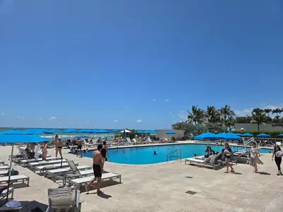 a group of people walking around a swimming pool at Lujoso Departamento Con VIstas Al Mar- Miami Beach in Sunny Isles Beach