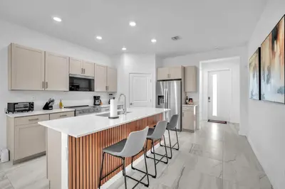 a kitchen with white cabinets and a counter with stools at Royal Palm Gateway - Spacious Family Retreat in Sunny Homestead in Homestead