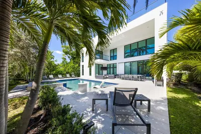 a house with a swimming pool and palm trees at LVS Villa Blanco 5BR Coastal Oasis with Rooftop Sunset Deck Heated Pool Spa & Walk-to-Beach Access in Fort Lauderdale