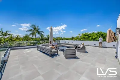 a group of people sitting on the roof of a building at LVS Villa Blanco 5BR Coastal Oasis with Rooftop Sunset Deck Heated Pool Spa & Walk-to-Beach Access in Fort Lauderdale