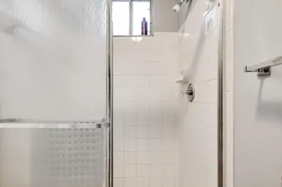 a white bathroom with a shower with a glass door at 2 Br 2 Bath Waterfront Apt Walking To Beach in Hallandale Beach