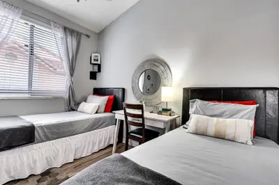 a bedroom with two beds and a desk with a mirror at 2 Br 2 Bath Waterfront Apt Walking To Beach in Hallandale Beach