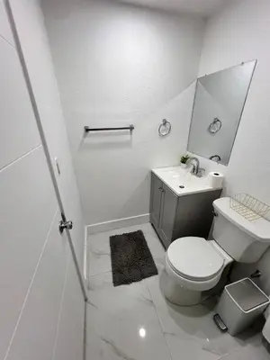 a white bathroom with a toilet and a sink at Miami City Escape in Hialeah