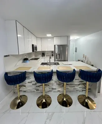 a kitchen with a counter with four blue bar stools at Miami City Escape in Hialeah