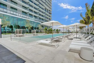 a pool with lounge chairs and umbrellas in front of a building at New 1Bed 1 bath Ocean view in Miami Beach