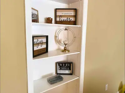 a book shelf with pictures and a clock on it at Lovely 2 Bedroom Condo With Free Parking & Wifi!! in Sunrise