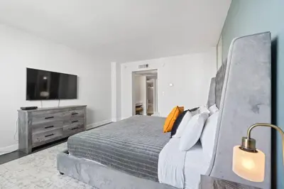 a bedroom with a bed and a flat screen tv at SUNNY ISLES 4BR Pool & Beach Access in Sunny Isles Beach