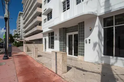 a white building on a sidewalk next to a street at So South Beach in Miami Beach