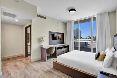 a bedroom with a bed and a desk and a television at New Luxury Beachfront Condo with Rooftop Pool in Hollywood