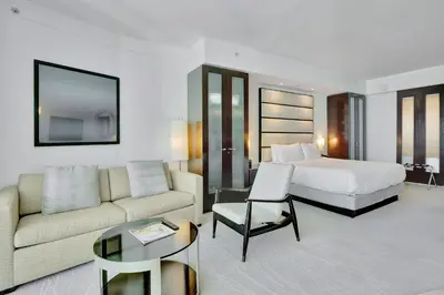 a hotel room with a bed and a couch and a table at Luxury Oceanview Suite at the Fontainebleau Miami Beach with Balcony, King & Sofa Bed in Miami Beach