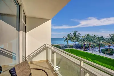 a balcony with a view of the ocean and palm trees at Spectacular 1-Bedroom Sea View Luxury & Comfort in Miami Beach