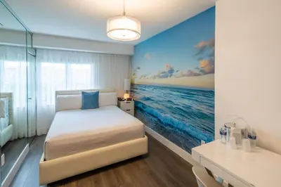a bedroom with a bed and a painting of the ocean at President Hotel Villa in Miami Beach