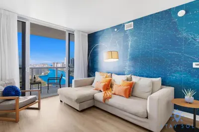 a living room with a white couch and a blue wall at Stylish 2BR High-Rise Retreat w Ocean Views in Hallandale Beach
