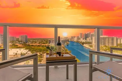a view of a city skyline from a balcony with a bottle of wine at Stylish 2BR High-Rise Retreat w Ocean Views in Hallandale Beach