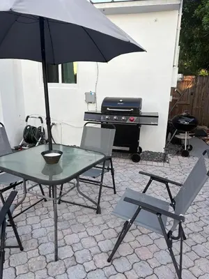 a table and chairs with an umbrella and a grill at Mid-Century with Outdoor Oasis in Fort Lauderdale