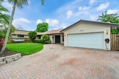 a house with a garage on a brick driveway at Fox Island Heated Spa- Downtown & Beach home in Fort Lauderdale