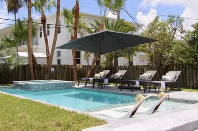 a swimming pool with chairs and an umbrella at Friendly Fox Luxury Pool & Spa - Near DT & Beach home in Fort Lauderdale