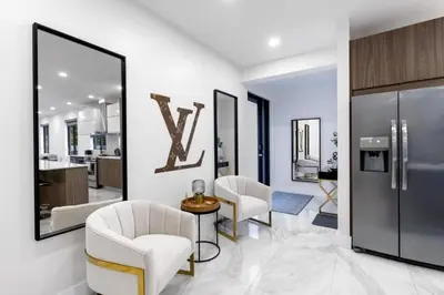 a living room with two white chairs and a large mirror at Golden Fox Downtown Pool House home in Fort Lauderdale