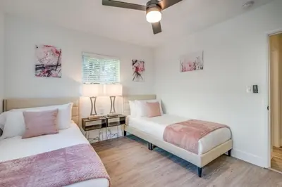 two beds in a room with white walls and wooden floors at Fox Private Resort- Near Downtown & Beach home in Fort Lauderdale