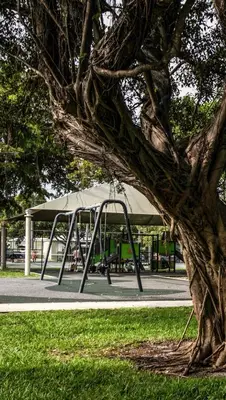 a swing set in a park with a tree at Designer Gem Condo - 5 Mins to Sand, Playground, Tennis, Free Parking in Hollywood